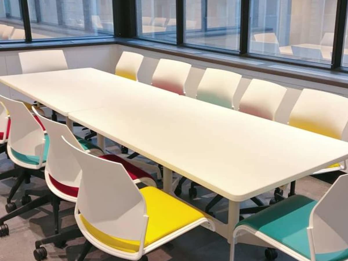 A bright meeting room with a long table that has space for ten chairs